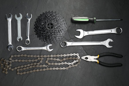 Parts of bicycles and tools on black table, flat lay