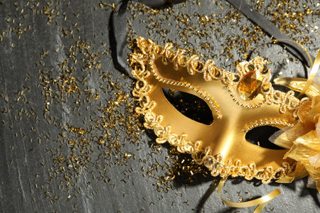 Beautiful golden carnival mask and confetti on gray textured table, top view. Space for textの写真素材
