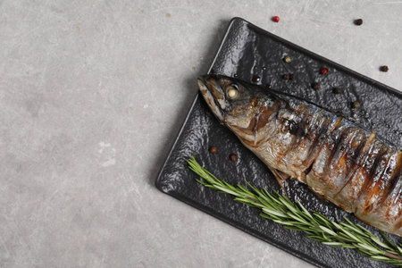 Delicious grilled mackerel, rosemary, lemon and peppercorns on gray table, top view. Space for text