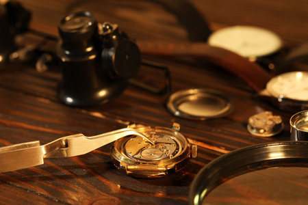 Mechanism of vintage wrist watch and tool on wooden table, closeupの写真素材