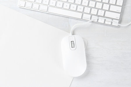 Computer mouse with mousepad and keyboard on light wooden table, flat lay