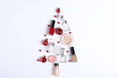 Christmas tree shape made of perfume bottles and cosmetic products on white background, flat layの写真素材