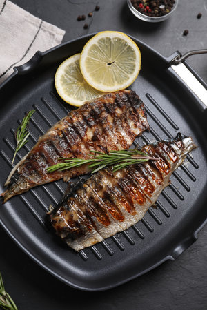 Delicious grilled mackerel, rosemary and lemon in pan on dark textured table, top viewの写真素材