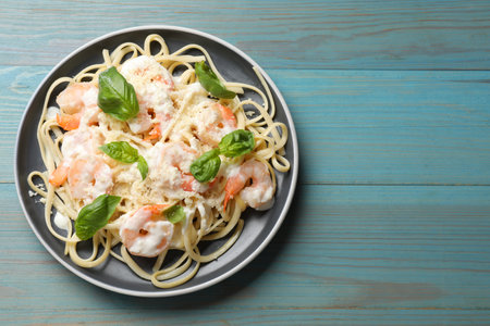 Tasty pasta with shrimps on light blue wooden table, top view. Space for textの写真素材