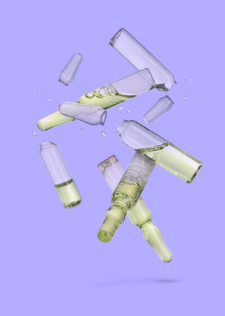 Many ampoules and glass pieces falling on light purple backgroundの写真素材