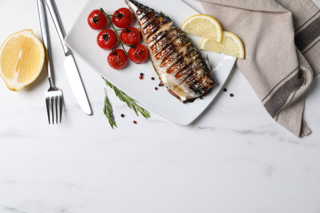 Delicious grilled mackerel, tomatoes and lemon served on white marble table, flat lay. Space for textの写真素材