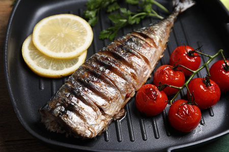 Delicious grilled mackerel, tomatoes, lemon and parsley in pan on table, closeupの写真素材