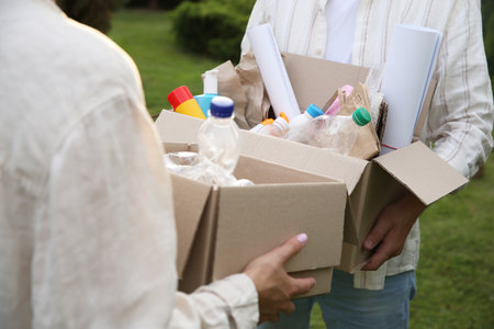 Recycling. People holding cardboard boxes with different garbage outdoors, closeup