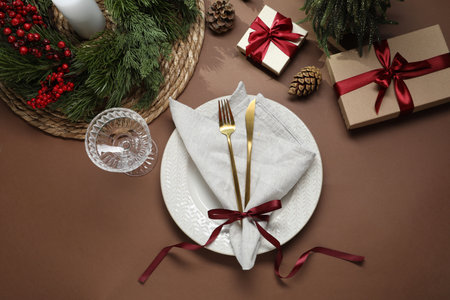 Christmas place setting with festive decor on brown table, flat lay
