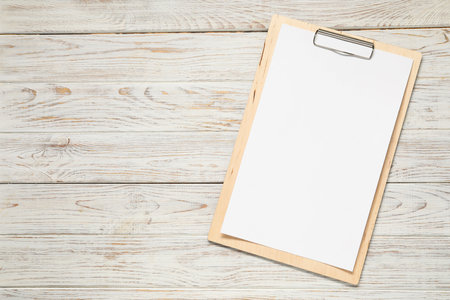 Clipboard with empty paper on wooden table, top view. Mockup for designの写真素材