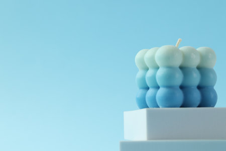 Beautiful bubble candle and podium on light blue background, closeup. Space for textの写真素材