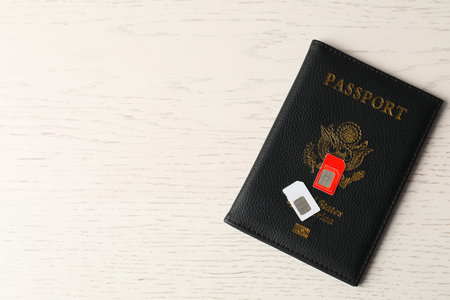Passport and SIM cards on white wooden table, top view. Space for textの写真素材