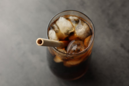 Tasty refreshing drink with straw in glass on gray table, closeup