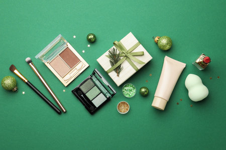 Flat lay composition with makeup products and Christmas decor on green backgroundの写真素材