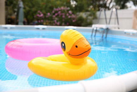 Inflatable rings floating on water in above ground swimming pool outdoors