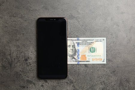 Modern smartphone and dollar bills on gray table, top viewの写真素材