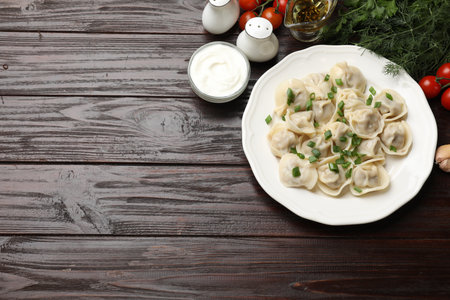 Delicious pelmeni with green onion served on wooden table, flat lay. Space for textの写真素材