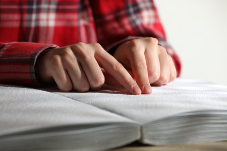 Blind woman reading book written in Braille at table, closeupの写真素材