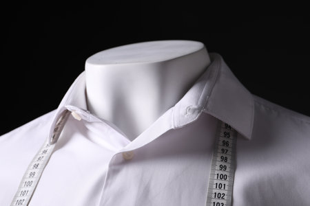 Male mannequin with white shirt and measuring tape on black background, closeupの写真素材