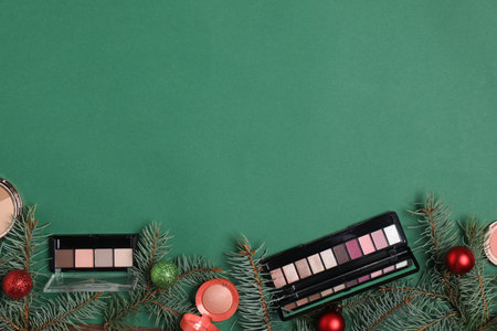 Flat lay composition with makeup products and Christmas decor on green background, space for textの写真素材