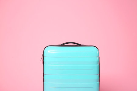 One new turquoise suitcase on pink background