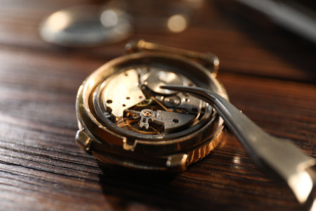 Mechanism of vintage wrist watch and tool on wooden table, closeupの写真素材