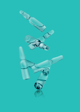 Many glass ampoules falling on turquoise backgroundの写真素材