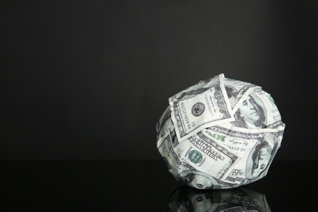 Ball made of dollars on black mirror surface. Space for textの写真素材