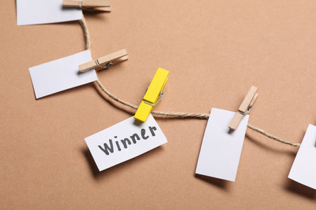 Paper note with word Winner among blank ones on rope against beige background, closeupの写真素材