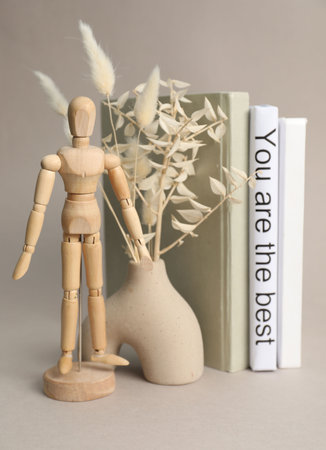 Wooden human figure, vase with decorative plants and white book with sentence You are the best between ones on light gray backgroundの写真素材