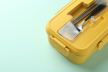 One lunch box with cutlery on light blue background. Space for textの写真素材