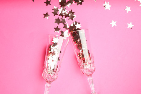 Wine glasses with confetti on pink background, flat lay. Christmas decorの写真素材