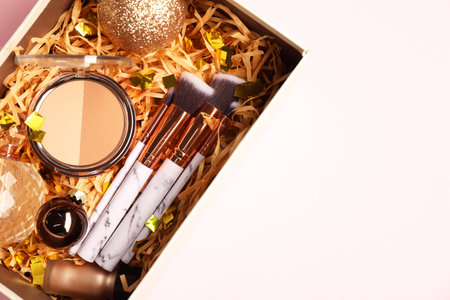 Makeup brushes, decorative cosmetics, perfume and Christmas decor in box on pink background, top view. Space for textの写真素材