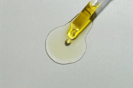Dripping essential oil from pipette on gray background, top viewの写真素材