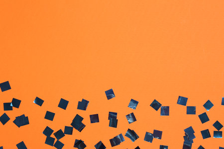 Shiny confetti on orange background, top view. Space for textの写真素材