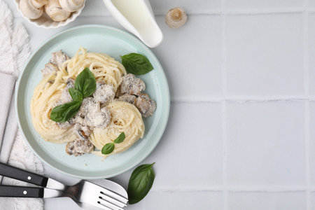Delicious pasta with mushrooms and basil served on white tiled table, flat lay. Space for textの写真素材