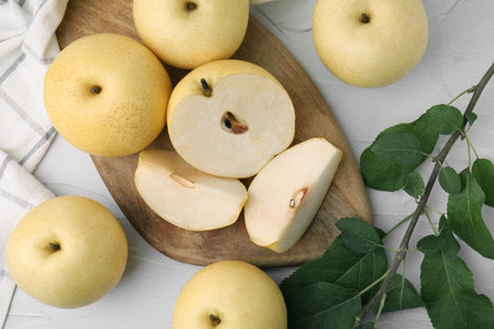Delicious fresh apple pears and green leaves on white table, top view