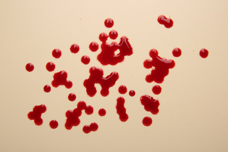 Drops of blood on beige background, top viewの写真素材