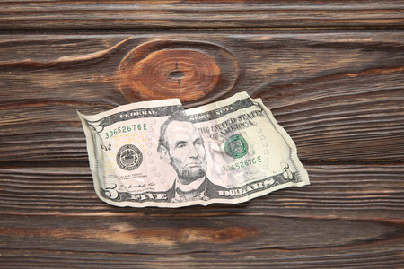 One crumpled dollar banknote on wooden table, top view