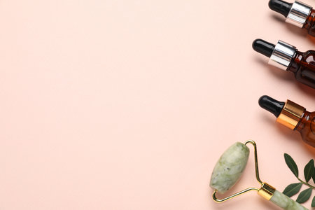 Different cosmetic products and green leaves on beige background, flat lay. Space for textの写真素材