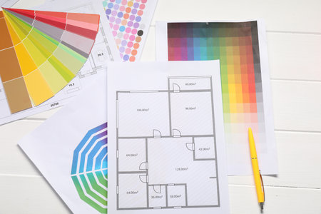 Designer's workplace with color palettes, floor plans and pen on white wooden table, flat layの写真素材