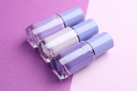 Nail polishes in bottles on color background, closeup