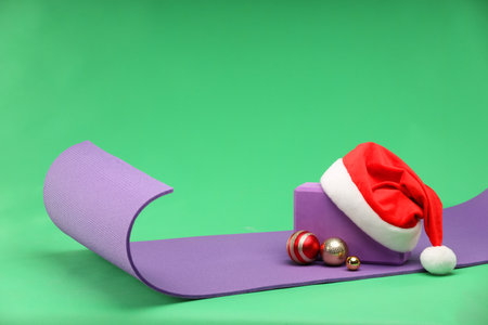 Yoga mat, block, Santa hat and baubles on green backgroundの写真素材