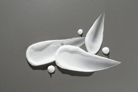 Smears of cosmetic products on gray background, top view
