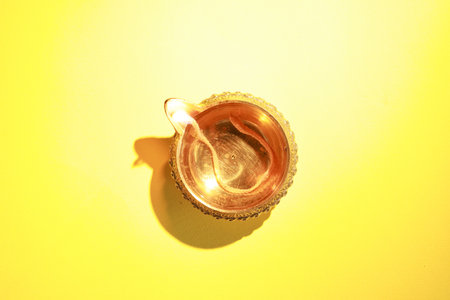 Diwali celebration. Diya lamp on yellow background, top view