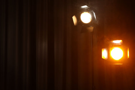 Professional spotlights against curtain in darkness. Space for textの写真素材