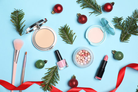 Flat lay composition with makeup products and Christmas decor on light blue backgroundの写真素材