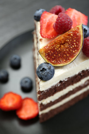 Piece of delicious chocolate sponge cake with berries on table, closeupの写真素材