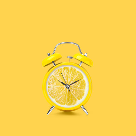 Juicy lemon on alarm clock dial against yellow background. creative posterの写真素材