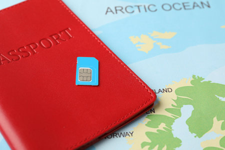 Passport and SIM card on world map, closeup